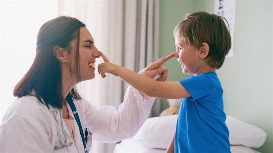 Illustrasjonsfotoet viser en gutt og en kvinnelige lege som smiler mot hverandre og tar på hverandres nesetipp