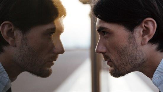 En mann ser på seg selv i et vindu.