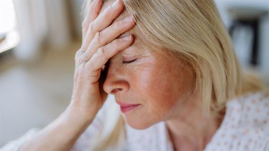 Illustrasjonsfoto: Kvinne med lyst hår holder hånden over pannen og lukker øynene.