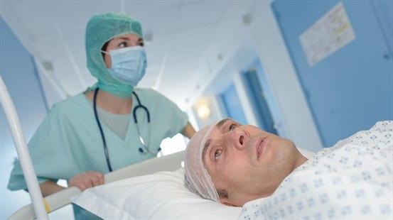 Hjerneoperert, sløvet pasient trilles bort fra operasjonsstuen.