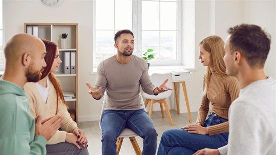 Illustrasjonsfoto av to kvinner og tre menn som sitter i en sirkel og har samtaleterapi.
