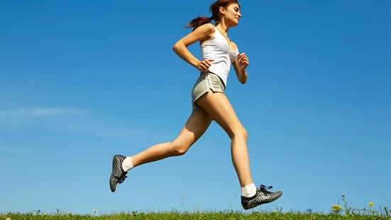 Dame i treningsklær som jogger på en blomstereng