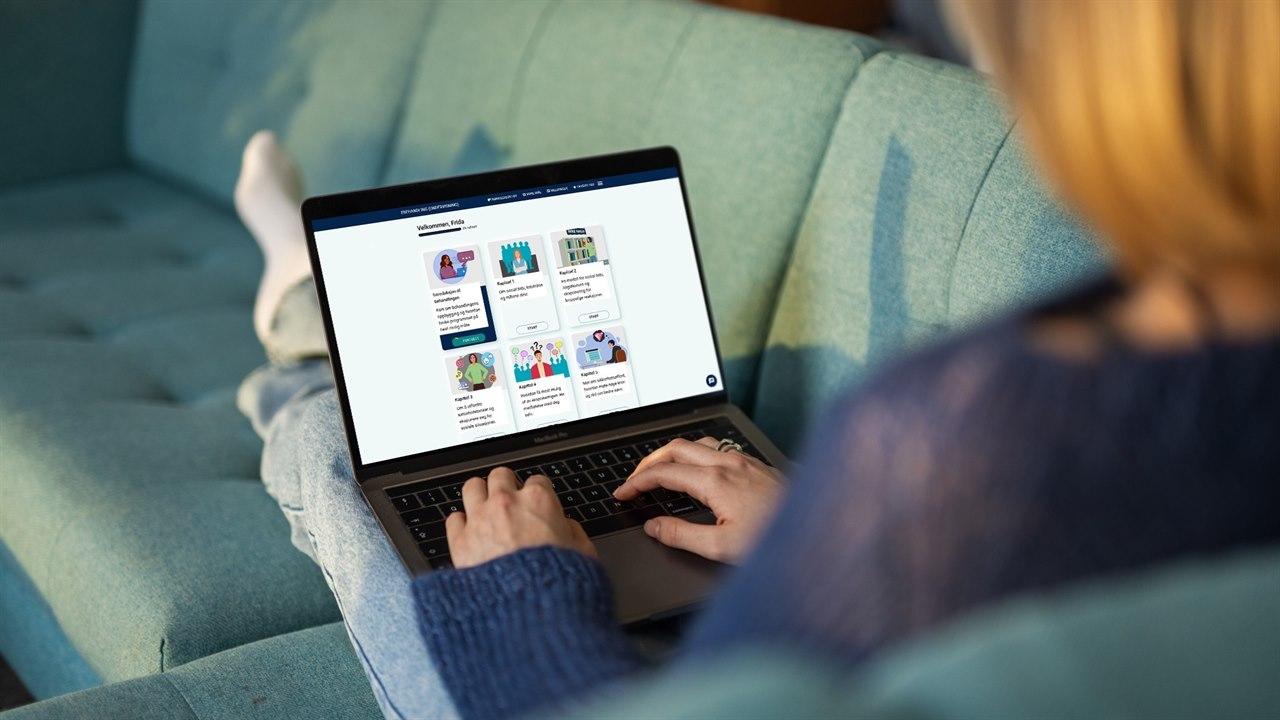 Illustrasjonsfotoet viser en kvinne som sitter i sofaen. Hun har en pc i fanget, der hun er inne på eBehandling. 