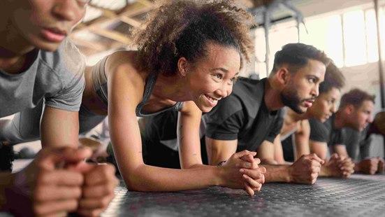 Illustrasjonsfoto: Seks unge menn og kvinner som trener planke ved siden av hverandre på et gym.