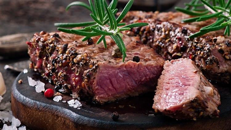 Illustrasjonsfoto av to oppskårne biff fileter som er godt krydret, hver med en kvist rosmarin på toppen