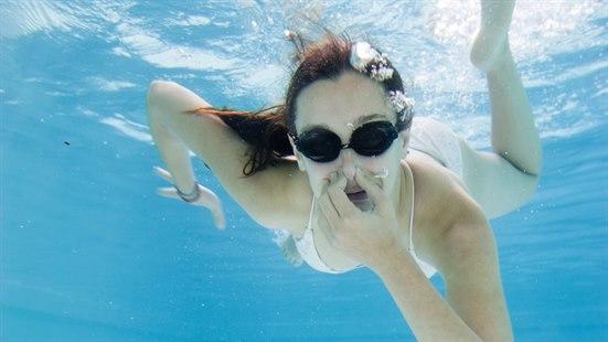 Illustrasjonsfoto av ei dame som dykker. Hun bruker svømmebriller og holder seg for nesen.