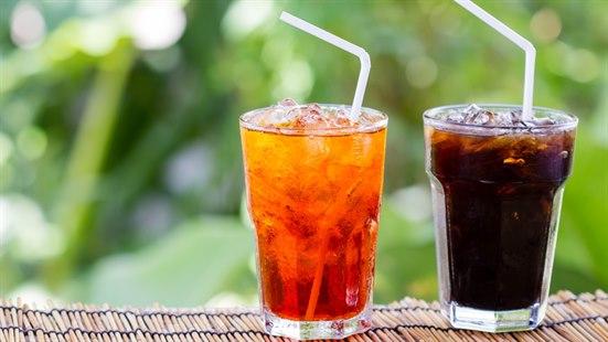 Illustrasjonsfoto av to glass med mørkebrun og lysebrun drikke står på et bord. Grønn vegetasjon i bakgrunnen.