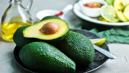 Tre avokadoer ligger på et fat. En avokado er delt i to.