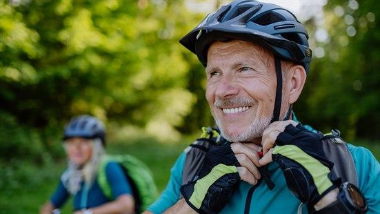 Illustrasjonsfoto av en mann på sykkeltur med en kvinne - han fester hjelmen under hodet.