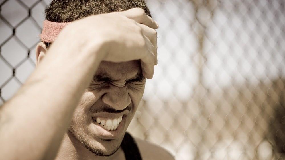 Mørkhudet mann som tar seg til hodet og gjør grimaser. Hodesmerte eller tabbe?