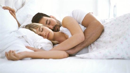 Illustrasjonsfoto av et par som sover sammen i en seng, hvor mannen holder rundt kvinnen.