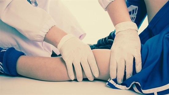 Nærbilde av leggen til et barn som blir undersøkt av en lege