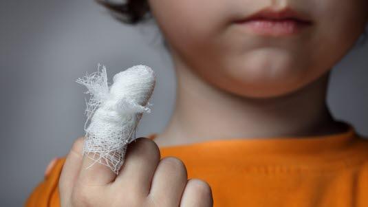 Et barn holder opp sin bandasjerte finger