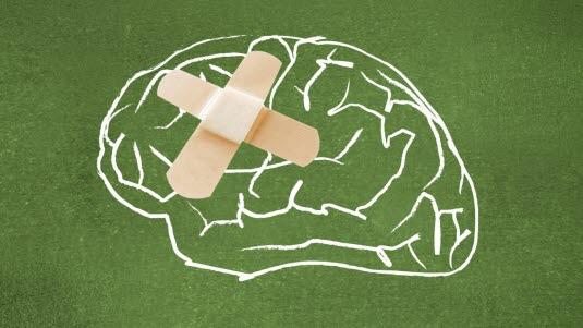 En hjerne tegnet med hvit kritt på et grønt papir, som har to plaster i kryss på venstre side