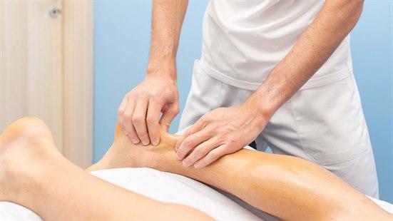 Illustrasjonsfotoet viser den venstre ankelen til en pasient som ligger på magen, hvor fysioterapeut kjenner på akillessenen