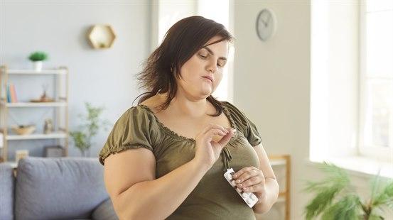 Overvektig ung kvinne som vurderer tabletter. 