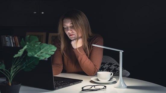 Bilde av kvinne som leser på laptop i mørket.