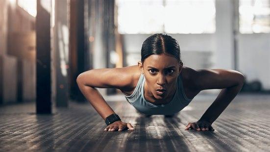 Illustrasjonsfoto: Kvinne som tar armhevinger i stort treningslokale