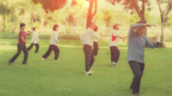 Illustrasjonsfoto av en gjeng mennesker i en park som driver med tai chi.