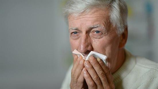 Illustrasjonsfoto av en eldre mann som hoster. Han holder et tørkle over munnen.