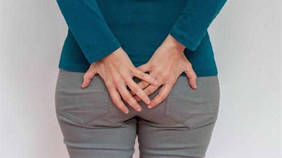 Illustrasjonsfotoet viser en kvinne som holder seg mot halebeinet