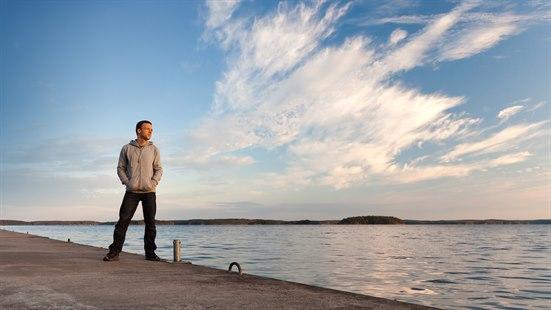 Mann står alene ved sjøen