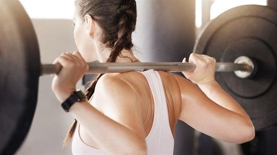 Illustrasjonsfoto: Vi ser ryggen, bakhodet og skuldrene på en kvinne som står med en vektstang over skuldrene.