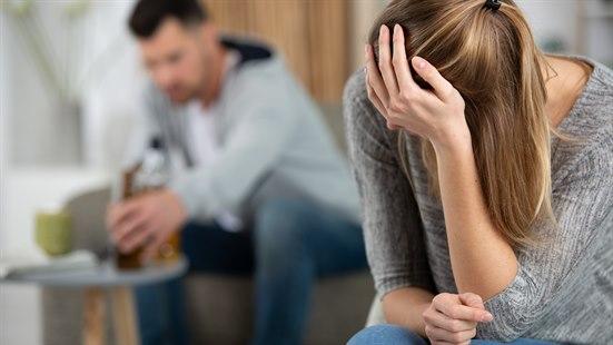 Illustrasjonsfoto av et par som sitter i sofaen. Kvinnen ser deprimert ut og hviler hodet i hånda.