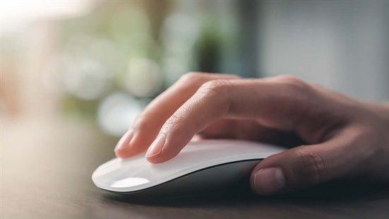 Illustrasjonsfoto av en hånd som hviler på en Apple datamus. Fingerspissene er lett plassert på musens overflate og håndflaten er flat og avslappet.