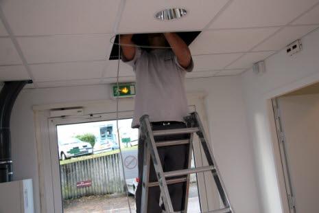 Elektriker som arbeider med lyset som festet i taket