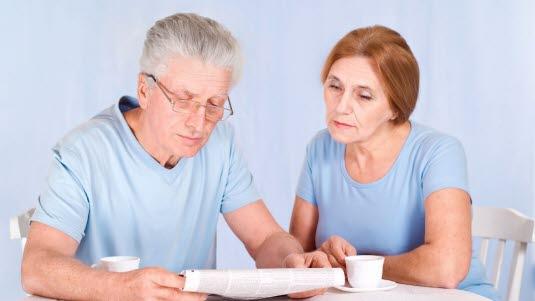 Illustrasjonsfotoet viser et eldre ektepar som sitter ved kjøkkenbordet