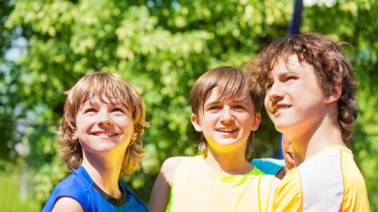 Illustrasjonsbilde av tre gutter i tenårene som står tett sammen ute i naturen.