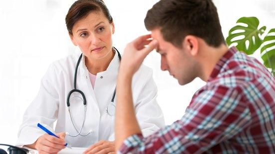 Illustrasjonsfoto viser en konsultasjon hos legen. Pasienten sitter med hånden mot ansiktet og ser tung ut mens han ser ned