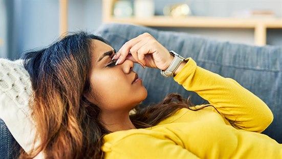 Illustrasjonsfoto av kvinne som ligger i en sofa.  Hun holder tre fingre over nesebeinet.