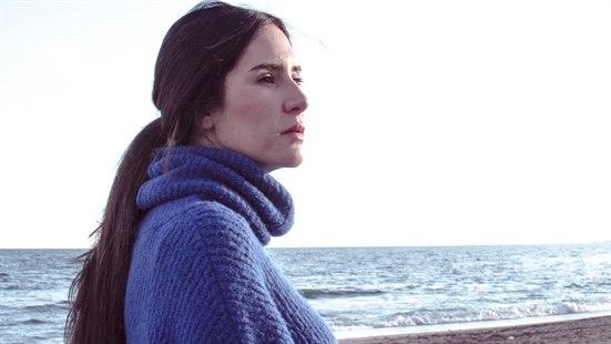 Illustrasjonsfotoet viser en alvorlig kvinne med hav i bakgrunnen. Kvinnen har langt mørkt hår i hestehale og lilla ullgenser