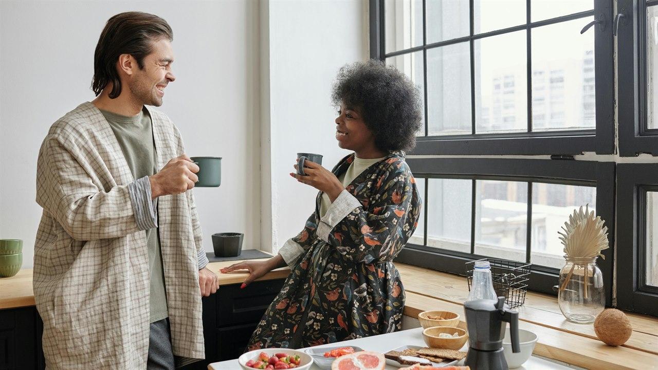 Illustrasjonsfotoet viser en kvinne og en mann som prater og ler på kjøkkenet