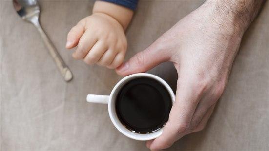 Illustrasjonsfoto viser hånden til en voksen og til et småbarn, den voksne holder en kaffekopp.