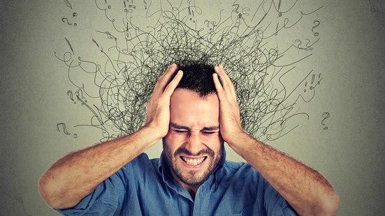 Illustrasjonsfoto av en mann som har masse tanker som strømmer inn mot hodet. Mannen holder seg for hode med begge hender og ser stresset ut.