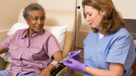 Illustrasjonsfotoet viser en kvinne som sitter i en stol og får en injeksjon av en kvinnelig sykepleier