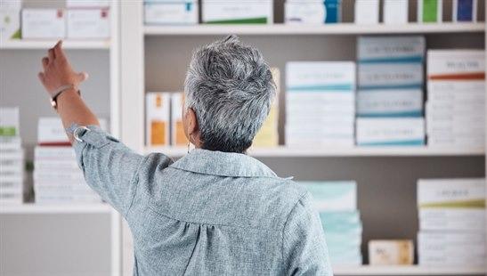 Illustration photo of a pharmacist reaching for medicine on a shelf.