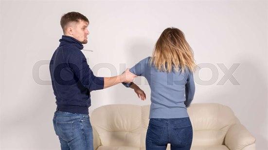 Mann tar tak i armen til en kvinne. Kvinnen står med ryggen til.