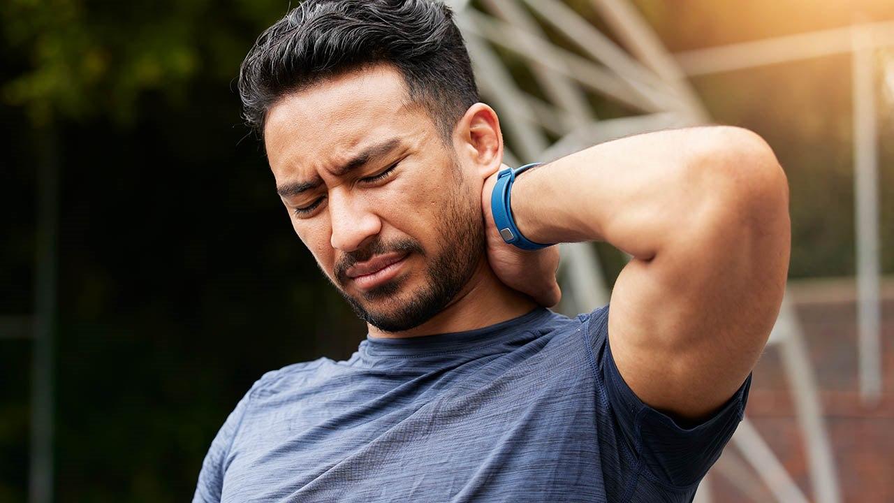 Illustrasjonsfoto av en mann som holder seg på nakken og ser ut til å ha nakkesmerter. Han uttrykker tydelig ubehag.