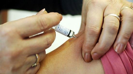 Fotoet viser hendene til en person som setter en vaksinesprøyte i skulderområdet til en annen person. 