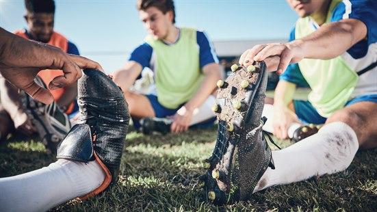 Illustrasjonsfoto av en gjeng fotballspillere som sitter på gressmatta og tøyer.