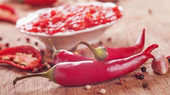 Illustrasjonsfoto av tre chilifrukt som ligger på en trebenk.