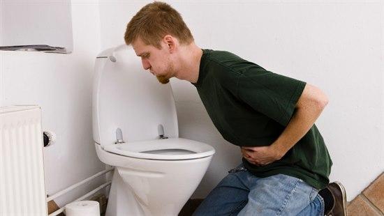 Voksen mann som sitter ved doskålen og har brekninger