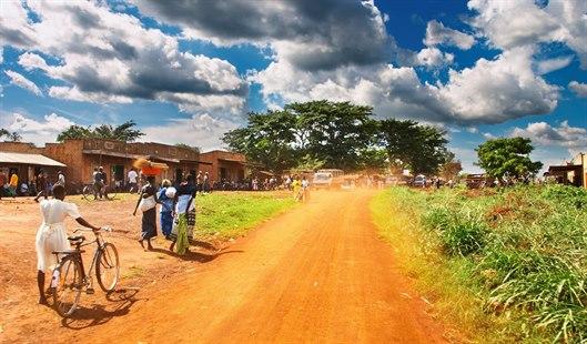 Illustrasjonsfotoet viser afriansk landsby. Vi ser mennesker ved husene og langs veien.