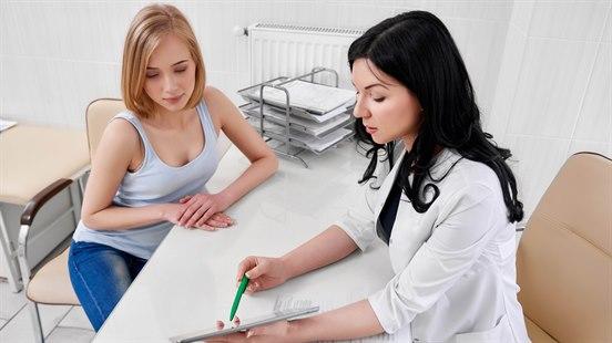 Kvinnelig lege og ung kvinne i samtale på legekontoret. 