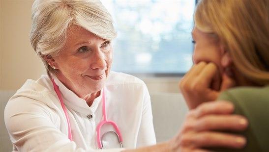 Illustrasjonsfotoet viser en kvinnelig lege som holder hånden over skulderen til en kvinne