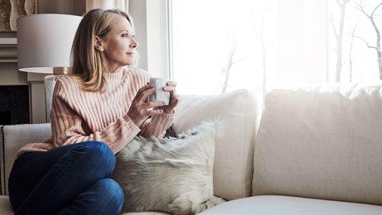 Illustrasjonsfotoet viser en middelaldrende kvinne som drikker kaffe i sofaen